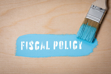 Fiscal Policy.  Blue paint and paint brush on wooden texture background