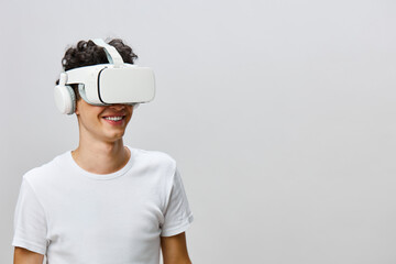 Virtual reality technology, immersive experience, young man with VR headset smiling on light gray background, exploring digital world concept, modern gadget usage, innovation in entertainment