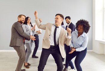 Happy office colleagues having fun, diverse mixed race friends dancing together, celebrating corporate success, profitable goal deal achievement, engaged in teambuilding activity, motivated for result