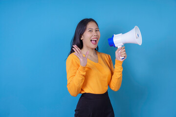 Young adult woman holding megaphone making an announcement with a surprised expression