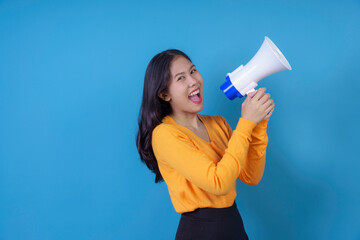Young woman is using a megaphone to make an announcement while smiling widely
