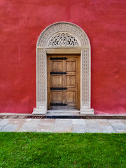 The wooden door on the red wall of the Zica monastery, Serbia