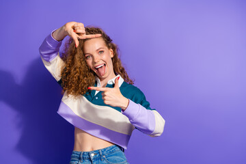Obraz premium Portrait of pretty lovely young girl show tongue cadre gesture isolated on purple color background