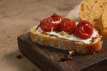 Traditional Italian bruschetta with cherry tomatoes, cream cheese and seasonings on a wooden board.