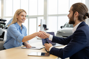 Fototapeta premium Rich woman customer client signing contract with salesman in car showroom