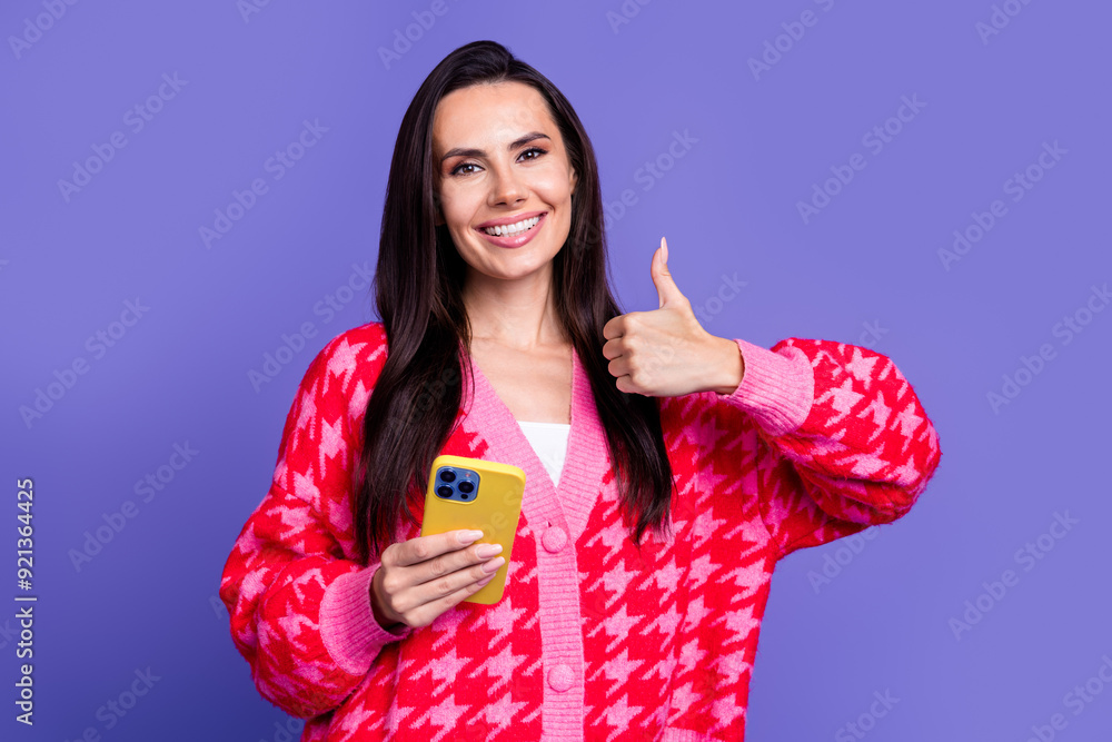 Poster photo of cheerful pretty lady dressed pink cardigan showing thumb up reading modern device isolated 