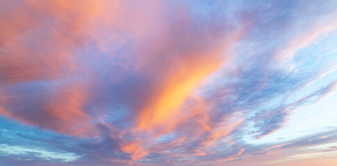 Brilliant hues of orange and pink mingle with delicate clouds as the sun sets over a serene ocean,...