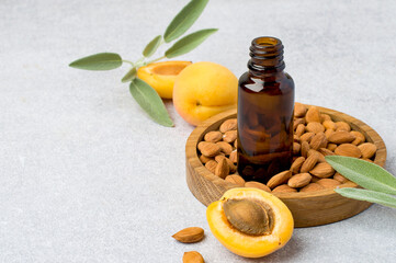 Apricot kernels in a wooden bowl, bottle, whole apricots, aroma of herbs, sage on a light...