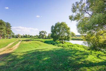 A grassy field with a road running through it and trees in the background