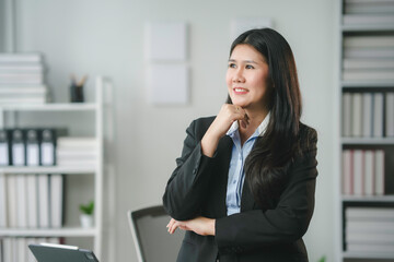 Confident businesswoman in modern office, smiling thoughtfully, immersed in work, embodying ambition and motivation. Symbolizing growth, achievement, and leadership in career