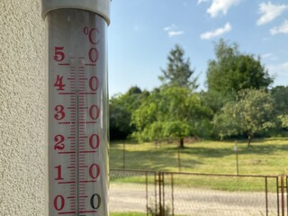 39,5 degrees Celsius on thermometer outside window in shade against trees with green leaves and blue sky on hot summer day in July in Poland. Topics: heat, climate, record temperatures in Europe