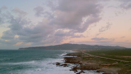 Dramatic seashore stormy ocean crashing of wild shore under cloudy evening sky.