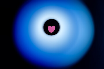 Pink heart surrounded by soft blue glow on black background.