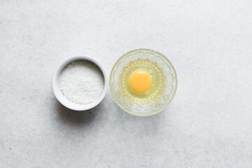 Overhead view of egg and sugar on a marble countertop, process of making meringue
