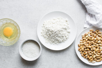 Overhead view of roasted peanuts flour egg and sugar on a marble countertop, flatlay of mise en place of ingredients for making coated peanuts, process of making nigerian coated peanuts