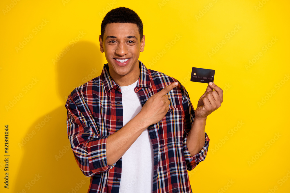 Sticker portrait of nice young man point finger debit card wear shirt isolated on yellow color background