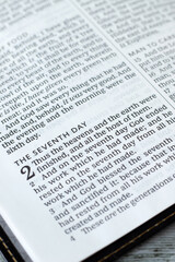 Obraz premium Seventh day Sabbath rest verses in open holy bible book. Close-up. Selective focus. Christian worship, blessing, obedience to God Jesus Christ, biblical concept.