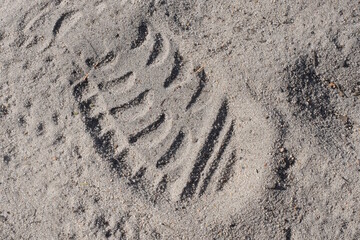 shoe sole print on the gray sand of the road in the street