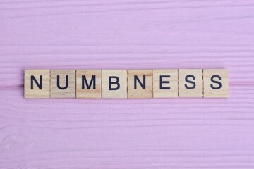 word numbness from gray wooden small letters with black font on an pink background