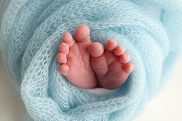 Close-up of tiny, cute, bare toes, heels and feet of a newborn girl, boy. Baby foot on blue soft coverlet, blanket. Detail of a newborn baby legs. Macro horizontal professional studio photo. 