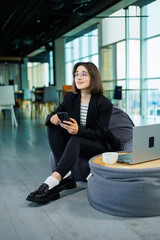 Young smiling professional businesswoman, happy confident female sales manager standing in modern office working online. A modern woman works on a laptop