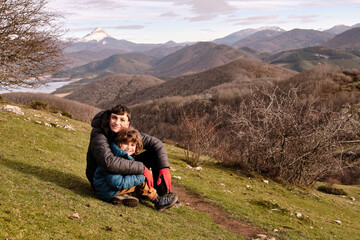 Fototapeta premium A portrait of two brothers sitting and embracing on the mountain.