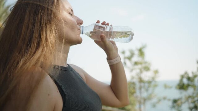 Quenching Her Thirst, a young woman drinks water with a serene backdrop. The refreshing drink complements the peaceful setting.