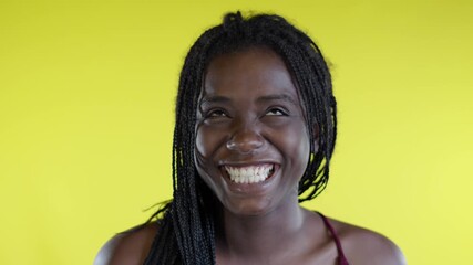 happiness and laughter. young black woman smiles and looks very happy. video on yellow background