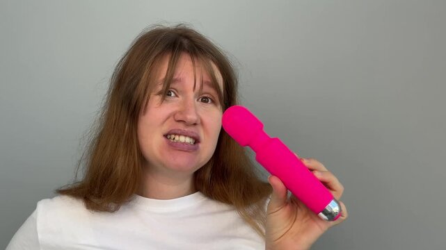 Confused young woman with sex toy for adults, female with vibrator 