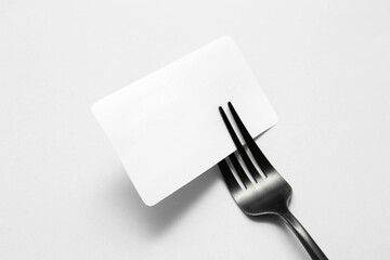 Blank card and stainless steel fork on white background