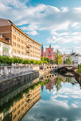 Early morning view towards Franciscan Church and Triple Bridge with reflection in Ljubljanica river in Ljubljana, Slovenia