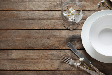 Plates with cutlery and glass on brown wooden background