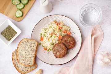 Cutlets with bulgur and boiled vegetables on light table in kitchen