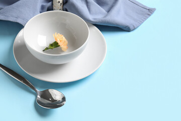 Beautiful table setting and eustoma flower on blue background, closeup