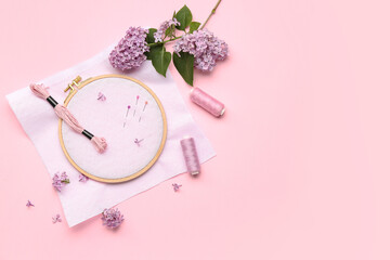Wooden embroidery hoop with canvas, mouline threads and ball pins on pink background