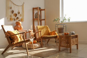 Interior of stylish living room with wooden furniture, armchairs and pumpkins
