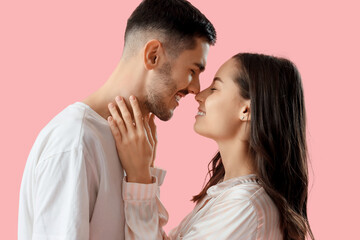 Happy young couple touching noses on pink background