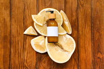 Bottle of cosmetic product and fresh pomelo on wooden background