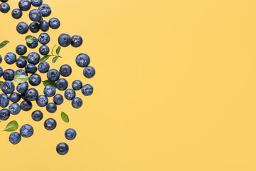 Flying sweet fresh blueberries and leaves on yellow background