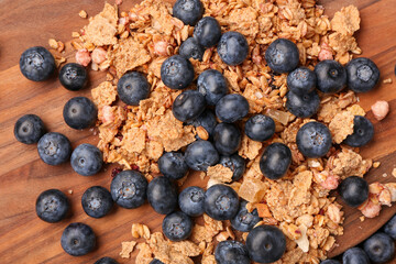 Sweet fresh blueberries and corn flakes on wooden background