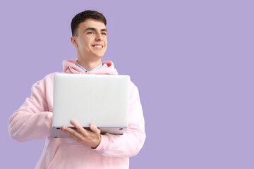 Obraz premium Young man with laptop on lilac background