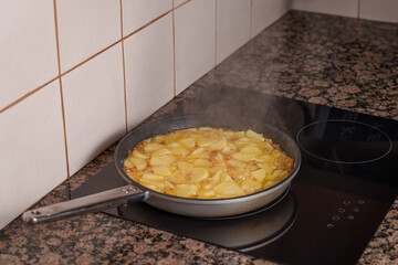 Frying potatoes in olive oil in a pan on an induction hob