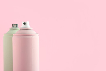 Spray paint cans on pink background
