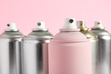 Spray paint cans on pink background
