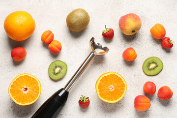 Blender, strawberries and different fruits on light grunge background