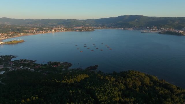 Aerial shot of the idyllic scenery of a lake surrounded by mountains at sunset in Nigran, Spain.