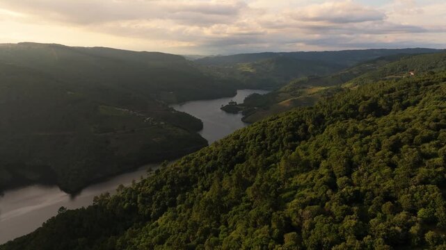 Aerial drone view over the river winding through lush green mountains in Marce, Spain.