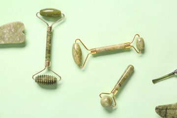 Different facial massage tools on green background