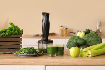 Glasses of healthy green smoothie with different fresh vegetables and fruits on table in kitchen