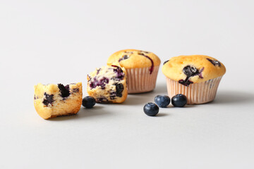Tasty blueberry muffins on light background